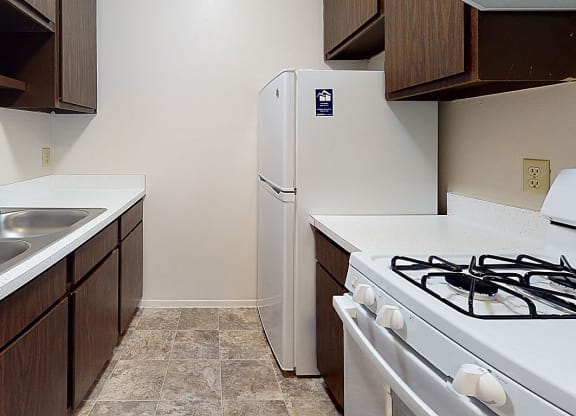 a gallery-style kitchen with a stove and a refrigerator at Newport Village Apartments, Portage