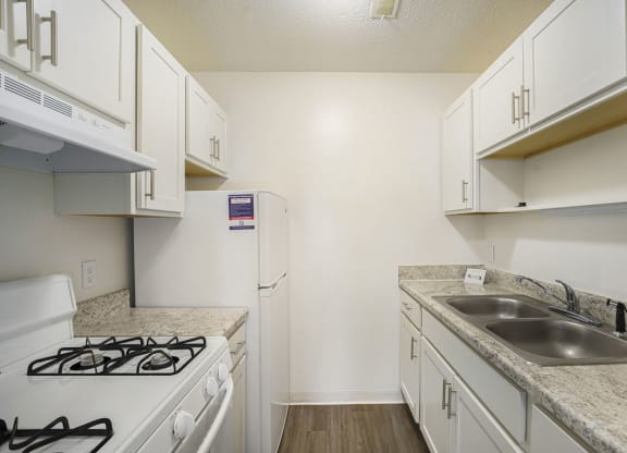 a kitchen with white cabinets and appliances at Newport Village Apartments, Portage, MI