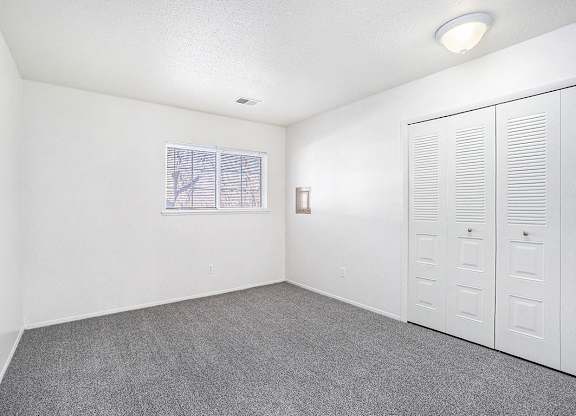 A bedroom with a window and a large closet at Newport Village Apartments, Portage, MI