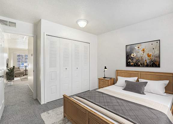 A bedroom with a bed, closet, and plush carpeting at Newport Village Apartments, Portage, MI
