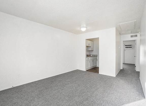 A living and dining room with plush carpeting at Newport Village Apartments, Portage, MI