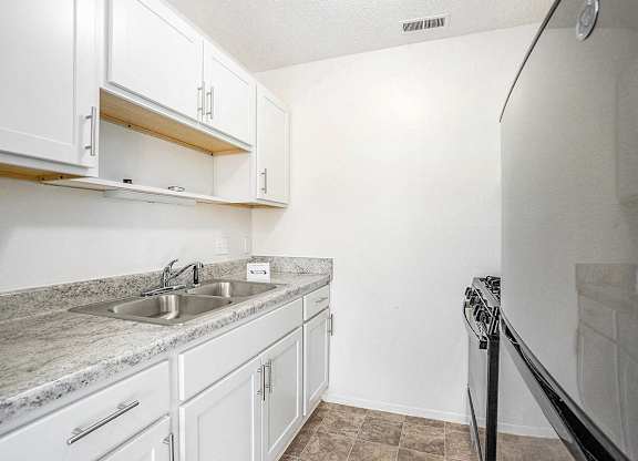 A kitchen with white cabinets and stainless steel appliances at Newport Village Apartments, Portage, MI