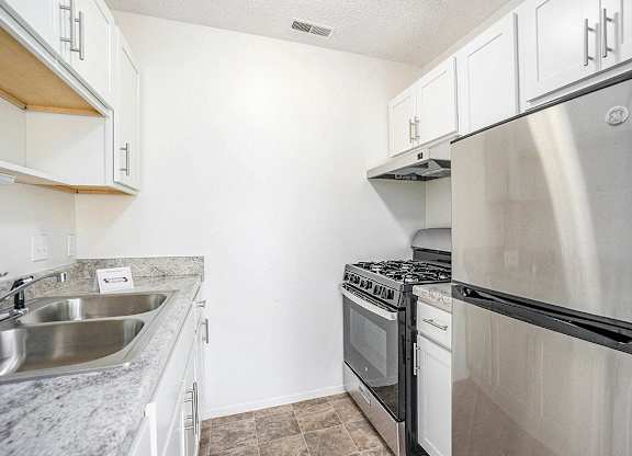 An upgraded kitchen with a stainless steel refrigerator and gas stove at Newport Village Apartments, Portage, MI