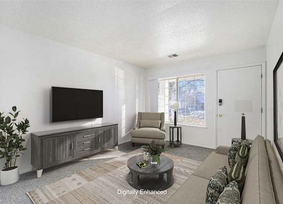 A living room with a flat screen TV, a sofa, and a coffee table at Newport Village Apartments, Portage, MI