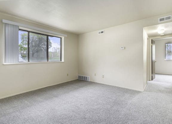 an empty living room with a large window and carpeting at Normandy Village Apartments, Michigan City, IN