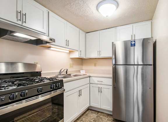 A kitchen with white cabinets and stainless steel appliances at Normandy Village Apartments, Michigan City
