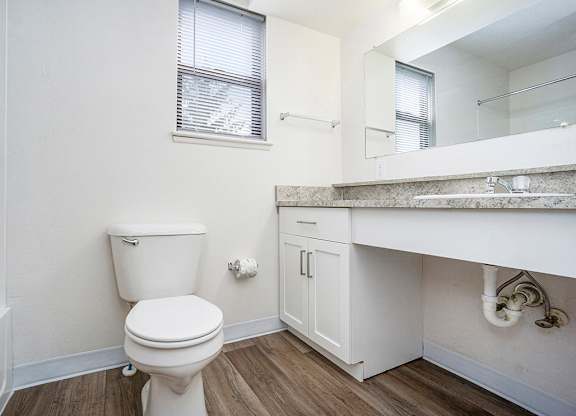 A white toilet sits in a bathroom with a window and white vanity at North Pointe Apartments in Elkhart, IN