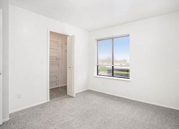 A bedroom with a large window and a door to a walk-in closet at North Pointe Apartments in Elkhart, IN