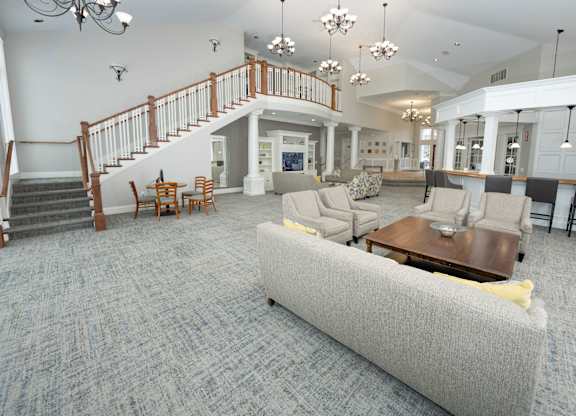A living room with a grey couch and a staircase  at Northport Apartments, Macomb, MI, 48044