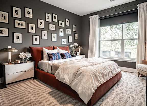 A bedroom with a large bed and a wall of picture frames.