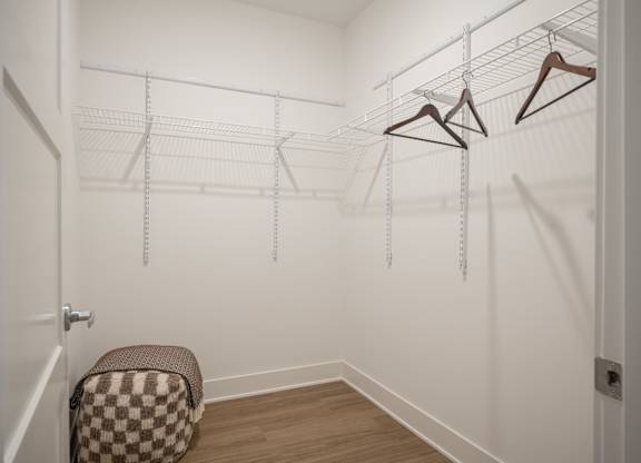 A white closet with a chair and hangers.
