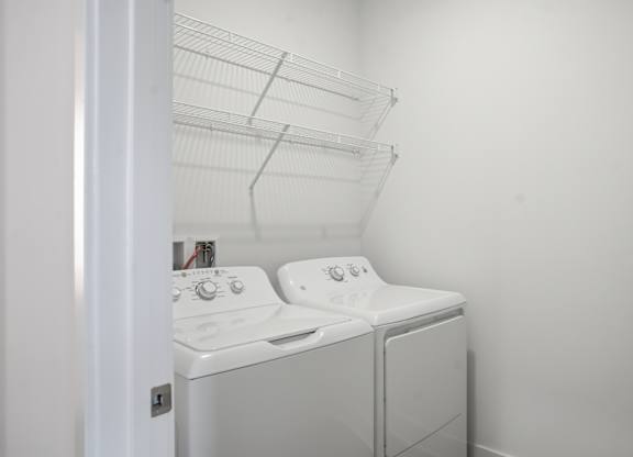 A white washing machine and dryer in a small laundry room at Nuvo Flats, Indiana, 46410