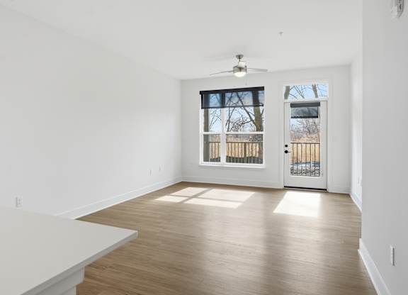 A room with a white table and a window with a view of a fence and trees at Nuvo Flats, Indiana, 46410