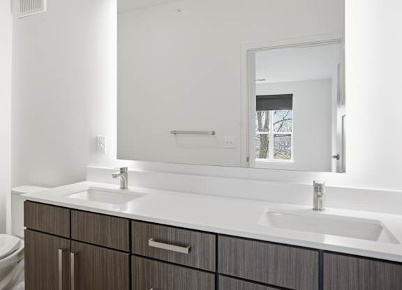A modern bathroom with a toilet, sink, and mirror at Nuvo Flats, Indiana, 46410