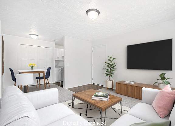 A modern living room with a white couch, a wooden coffee table, and a TV at Old Farm Apartments, Elkhart, Indiana