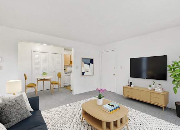 A living room with a grey couch, a wooden coffee table, and a flat screen TV on the wall at Old Monterey Apartments in Springfield, MO