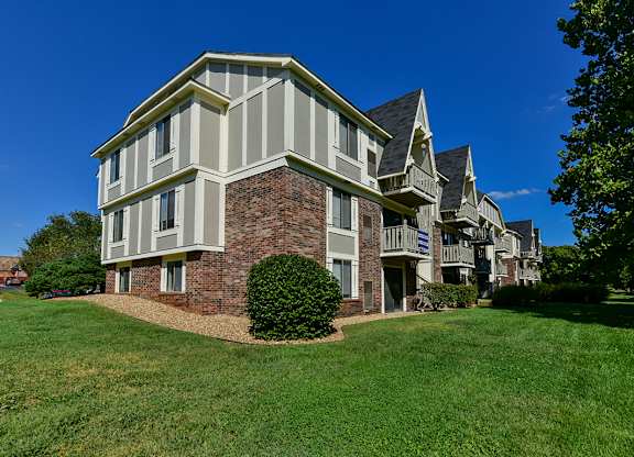 A large building with a brick base and white siding at Old Monterey Apartments, Springfield, MO