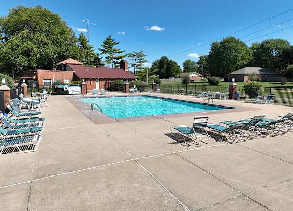 A pool surrounded by chairs and a building in the background at Old Monterey Apartments, Springfield, MO