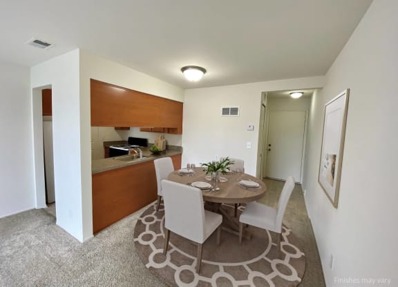 a dining area with a table and chairs and a kitchen in the background at The Landings Apartments, Westland, MI