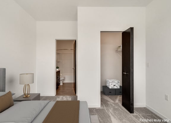 a bedroom with a bed and a door that leads to a bathroom  at Uptown Square Apartments, Michigan