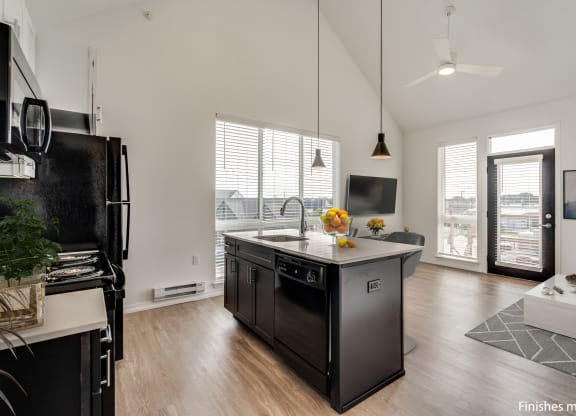 a kitchen with a large island and a view of a living room  at Uptown Square Apartments, Troy, MI