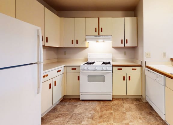 a kitchen with white cabinets and a stove and a refrigerator at Pine Knoll Apartments, Battle Creek, 49014