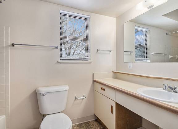 A white toilet is in a bathroom with a sink and mirror.