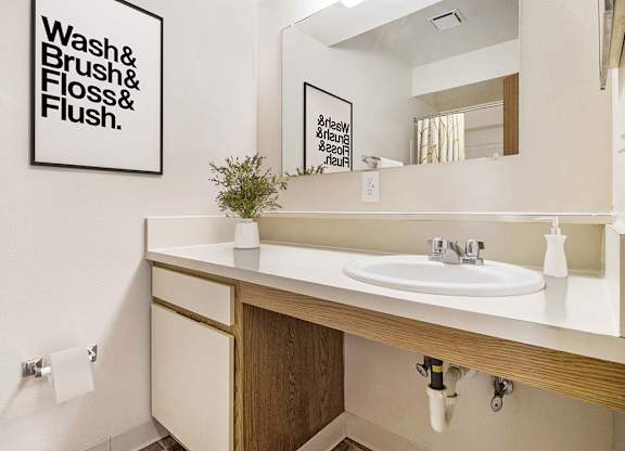 A bathroom with a sink and large mirror at Pine Knoll Apartments, Battle Creek