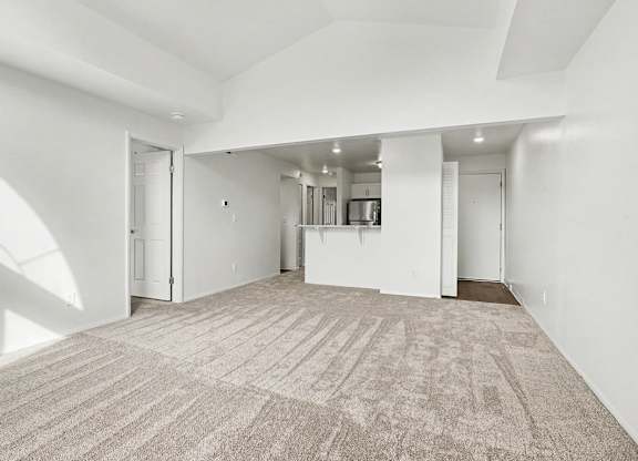 A large, empty dining room with a carpeted floor and white walls at Pine Knoll Apartments, Battle Creek