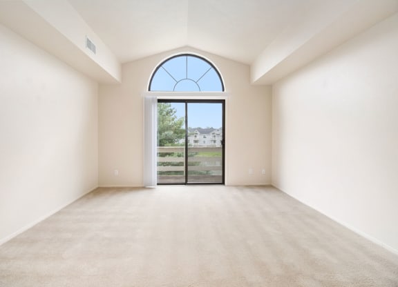 spacious living room with a cathedral ceiling and a slider to a balcony at Pine Knoll Apartments, Battle Creek, MI