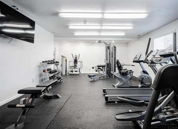 A well-equipped gym with various exercise machines and weights at Polo Run Apartments, Greenwood, Indiana