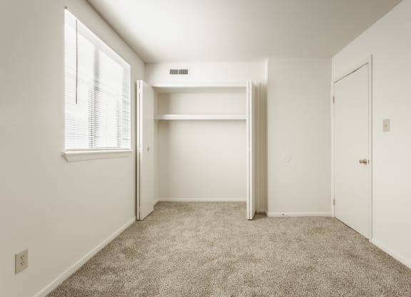 a bedroom with white walls and carpet and a closet at Polo Run Apartments, Greenwood