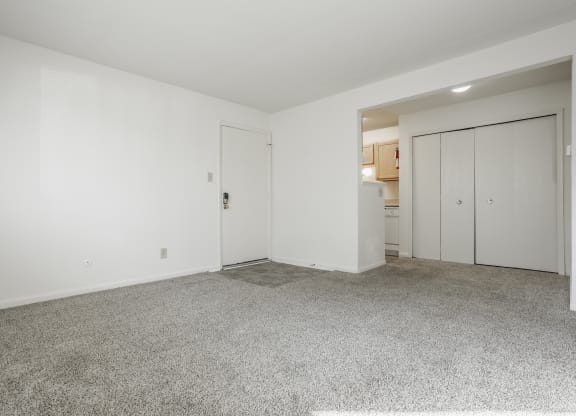 a living room with white walls and carpet and a door to a kitchen at Polo Run Apartments, Indiana, 46142