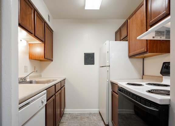 A small kitchen with a white refrigerator and a black stove top oven at Polo Run Apartments, Greenwood, 46142