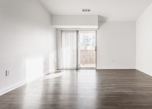 renovated expansive living room interior with plank flooring, white walls, and a glass slider door to the balcony  at Polo Run Apartments, Greenwood, IN, 46142