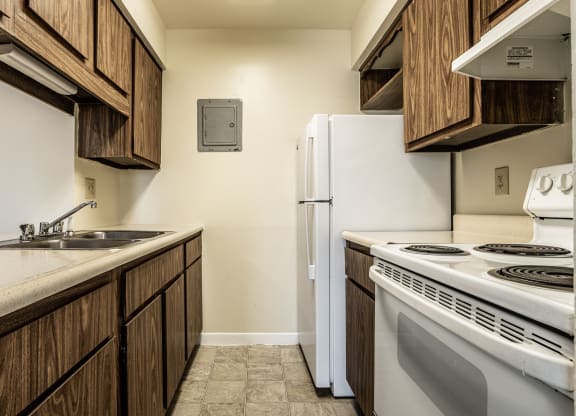 Kitchen with brown cabinetry and white appliances in Greenwood at Polo Run Apartments, Greenwood, IN