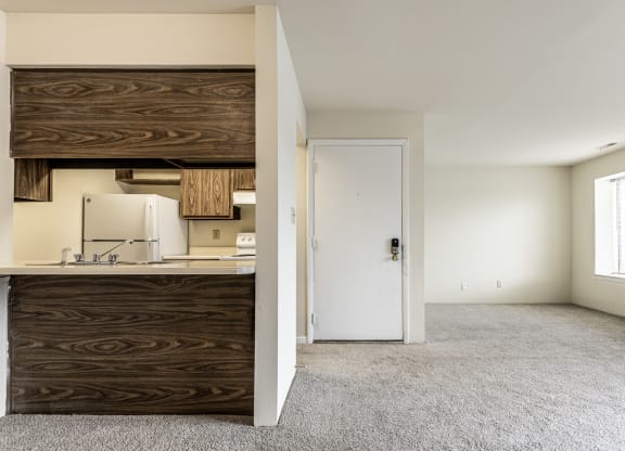 an empty living room with a kitchen and a door to a white room at Scarborough Lake Apartments, Indianapolis, 46254