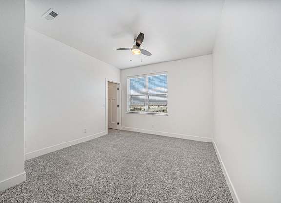 A bedroom with a ceiling fan, walk-in closet and carpeted floor at The Reserve at Destination Pointe, Iowa