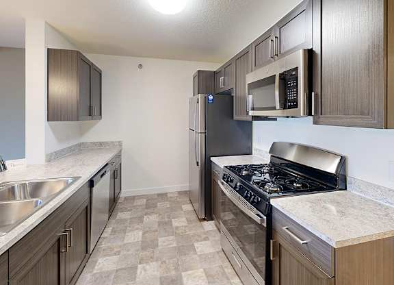 A kitchen with a stove, sink, and refrigerator at The Reserve at Destination Pointe apartments, Grimes, IA
