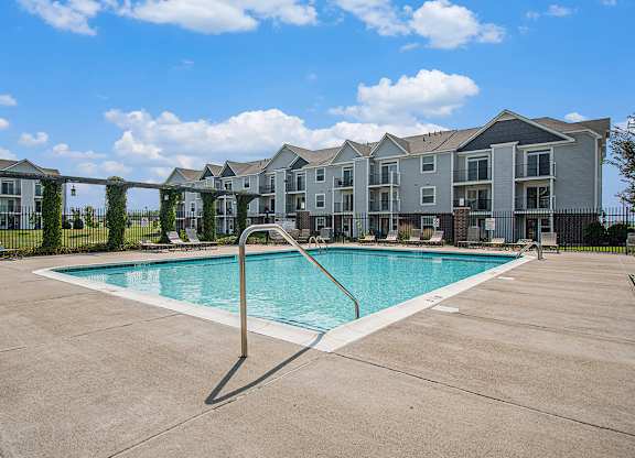 A swimming pool in front of apartment buildings at The Reserve at The Reserve at Destination Pointe in Grimes, IA 50111