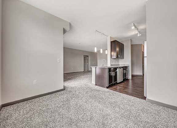 A spacious living room with a kitchen area in the background.at River Crossing Apartments, St. Charles, MO, 63303