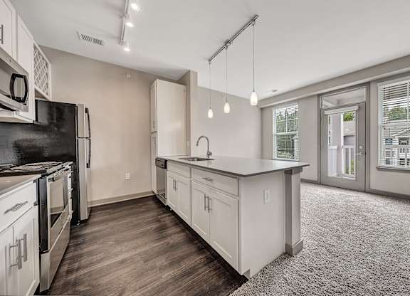 A kitchen with white cabinets and a black fridge. at River Crossing Apartments, St. Charles