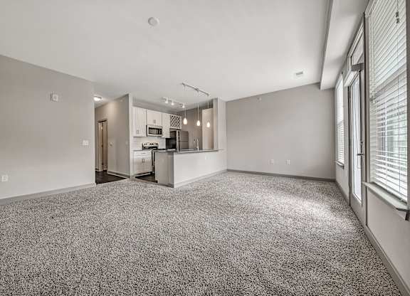 A spacious living room with a kitchen in the background.at River Crossing Apartments, St. Charles, MO