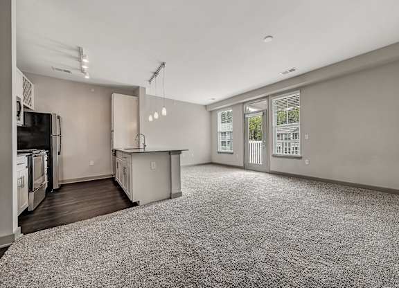 A spacious kitchen and living room with a grey carpet. at River Crossing Apartments, St. Charles, 63303