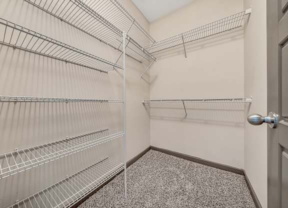 A walk-in closet with metal shelving and a carpeted floor. at River Crossing Apartments, St. Charles, Missouri