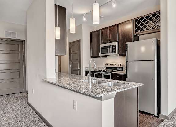 A kitchen with a granite countertop and stainless steel appliances. at River Crossing Apartments, St. Charles, MO