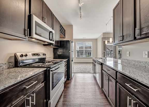 A modern kitchen with dark wood cabinets and granite countertops. at River Crossing Apartments, St. Charles, MO, 63303