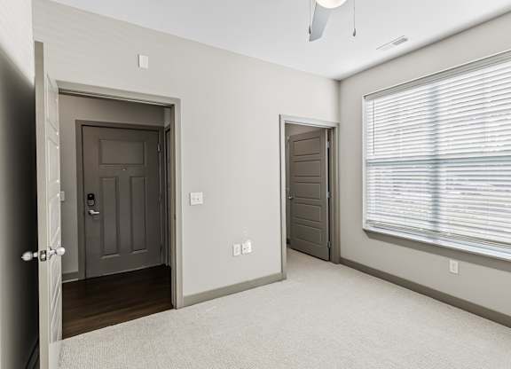 A room with a brown door, a window with blinds, and a white ceiling. at River Crossing Apartments, St. Charles, 63303