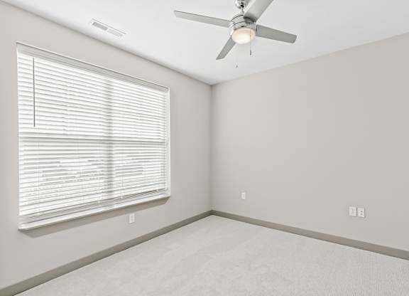 A room with a ceiling fan and a window with blinds. at River Crossing Apartments, St. Charles