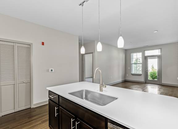 A modern kitchen with a white countertop and a stainless steel sink. at River Crossing Apartments, Missouri